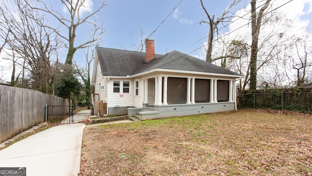 rear view of property featuring a sunroom and a yard