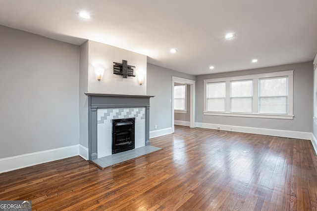 unfurnished living room featuring dark hardwood / wood-style flooring and a tile fireplace