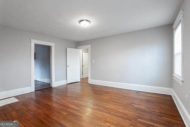 spare room with dark hardwood / wood-style flooring and a healthy amount of sunlight