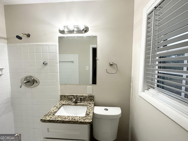 bathroom featuring vanity, tiled shower, and toilet