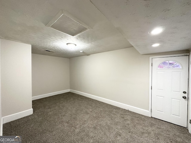 basement with a textured ceiling and dark colored carpet