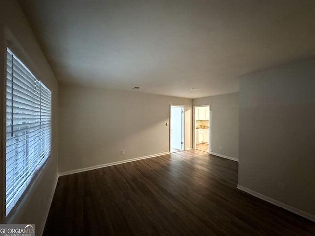 spare room featuring dark wood-type flooring and a healthy amount of sunlight