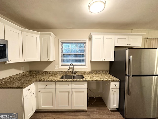 kitchen featuring appliances with stainless steel finishes, dark hardwood / wood-style floors, stone countertops, white cabinetry, and sink