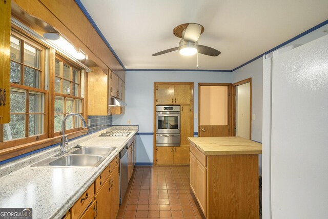 kitchen featuring sink, ceiling fan, appliances with stainless steel finishes, backsplash, and dark tile patterned flooring