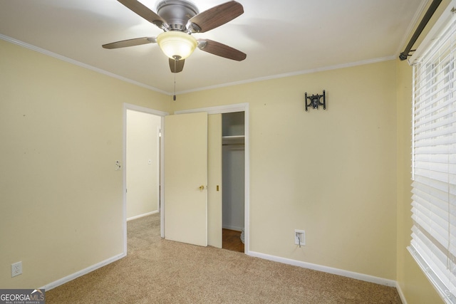 unfurnished bedroom with crown molding, light colored carpet, ceiling fan, and a closet