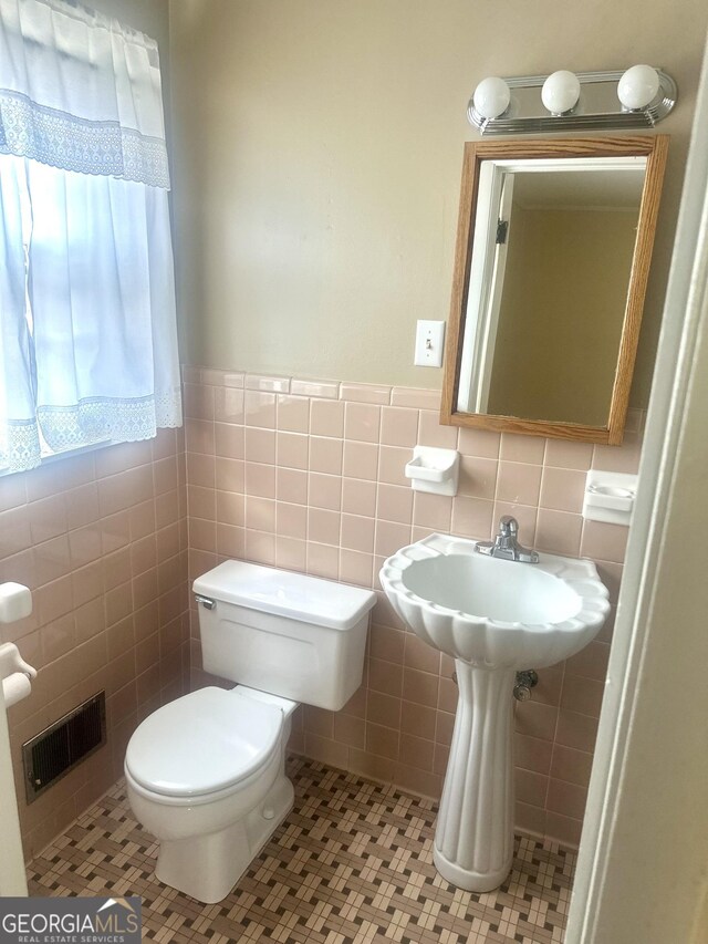 bathroom featuring toilet, tile patterned flooring, and tile walls