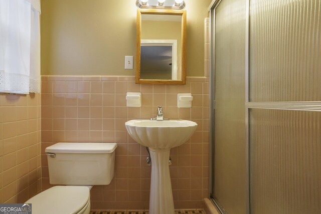 bathroom with walk in shower, tile walls, and toilet