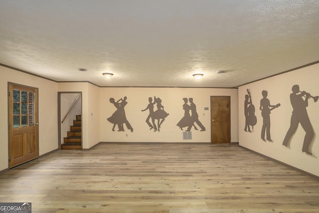 basement with crown molding, light hardwood / wood-style floors, and a textured ceiling