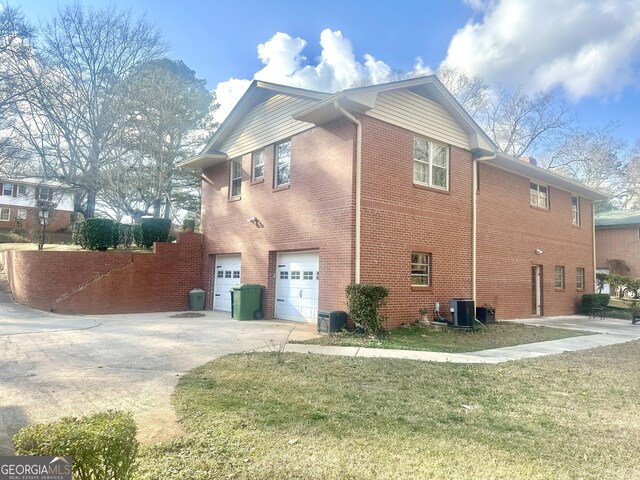 view of side of property featuring a garage, a lawn, and central air condition unit