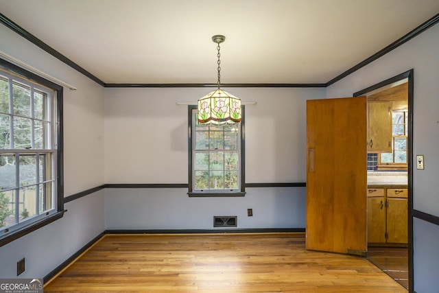 unfurnished dining area featuring light hardwood / wood-style flooring and ornamental molding