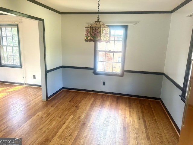 unfurnished room with crown molding, plenty of natural light, and hardwood / wood-style floors