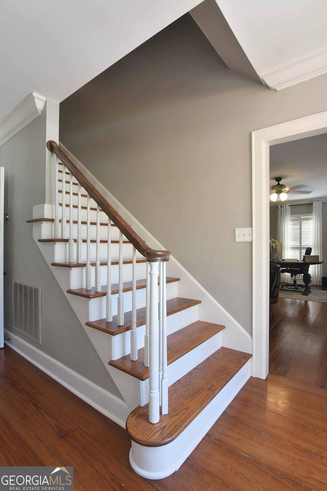 staircase with ceiling fan and wood-type flooring