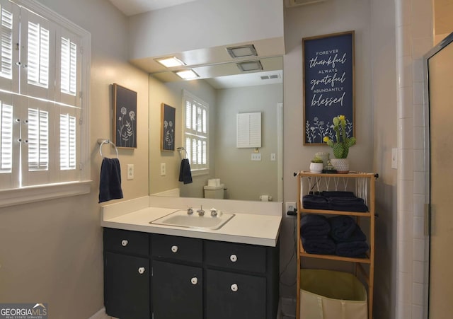 bathroom with vanity, toilet, a shower with door, and a wealth of natural light