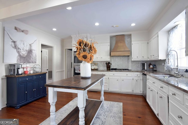 kitchen featuring blue cabinets, sink, wall chimney range hood, stainless steel appliances, and white cabinets