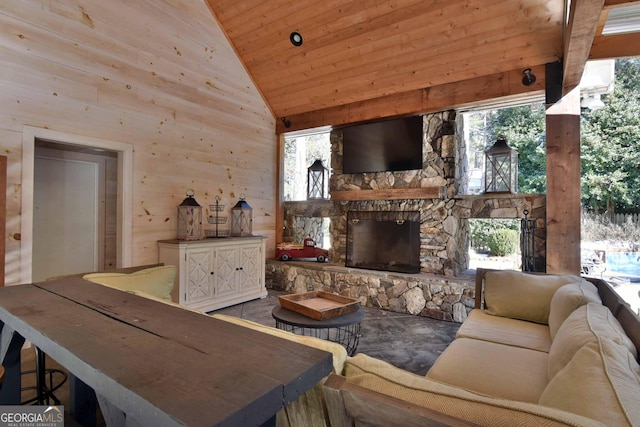 living room with wood ceiling, wooden walls, high vaulted ceiling, and an outdoor stone fireplace