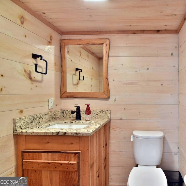 bathroom featuring vanity, wood walls, wood ceiling, and toilet