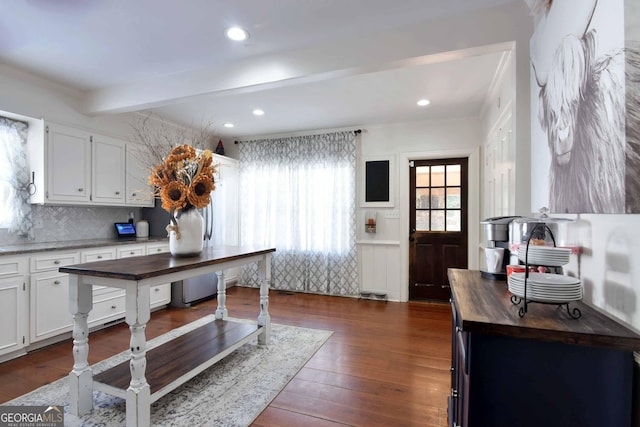 kitchen with butcher block countertops, dark wood-type flooring, tasteful backsplash, white cabinets, and beamed ceiling