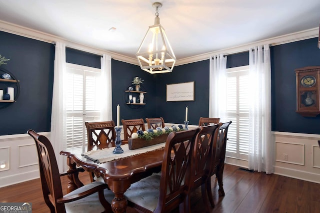 dining room featuring dark wood-type flooring, ornamental molding, plenty of natural light, and a chandelier