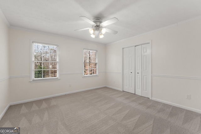 unfurnished bedroom with ceiling fan, a closet, ornamental molding, and light carpet