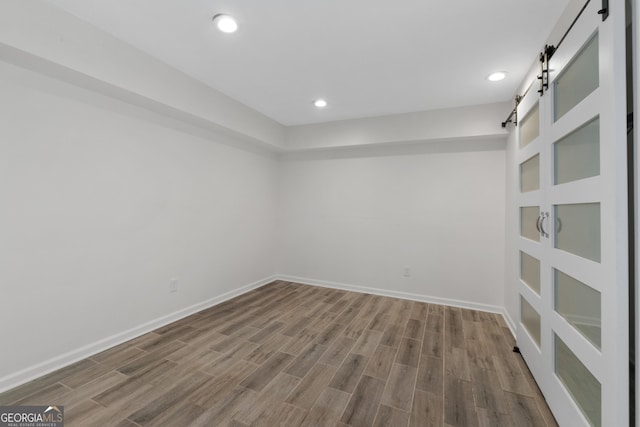 empty room with hardwood / wood-style flooring and a barn door