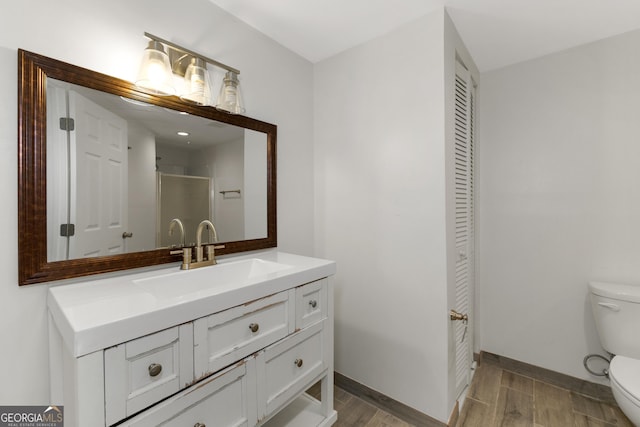 bathroom with vanity, hardwood / wood-style floors, a shower with door, and toilet