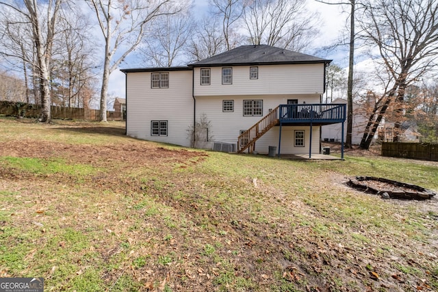 back of property featuring a wooden deck, a yard, and a fire pit