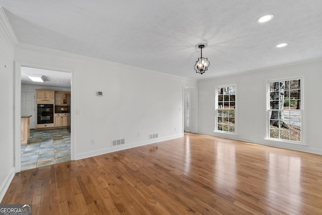 unfurnished living room featuring ornamental molding, a chandelier, a textured ceiling, and light wood-type flooring