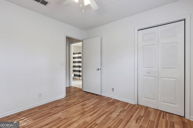 unfurnished bedroom with ceiling fan, a closet, and light wood-type flooring