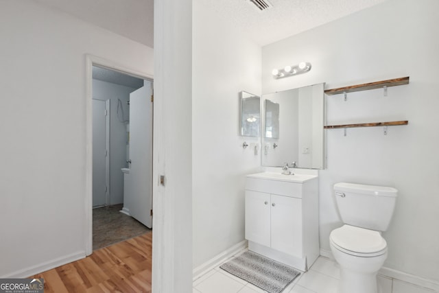 bathroom with hardwood / wood-style flooring, vanity, toilet, and a textured ceiling