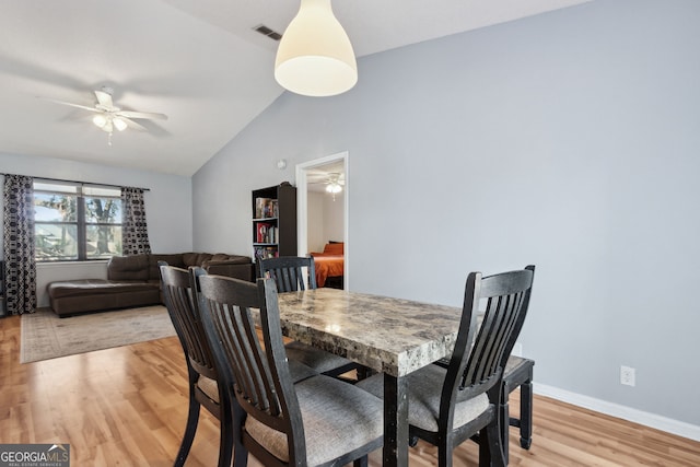 dining area featuring ceiling fan, lofted ceiling, and light wood-type flooring