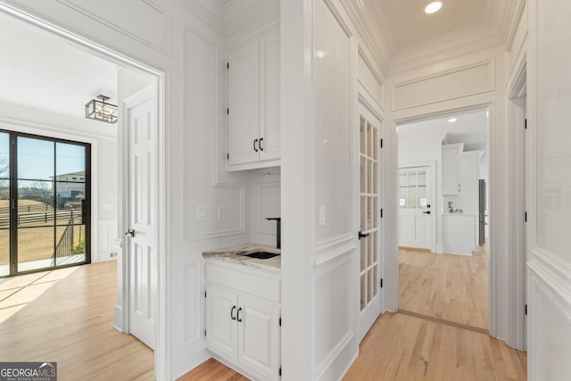 corridor featuring ornamental molding, sink, and light hardwood / wood-style floors