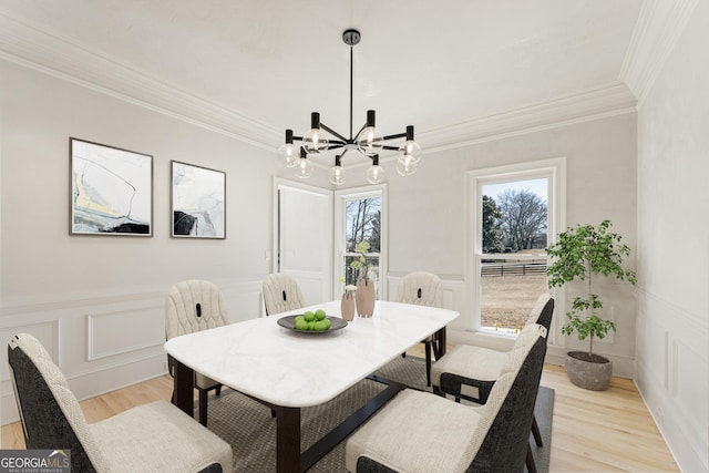 dining area with ornamental molding, a chandelier, and light wood-type flooring