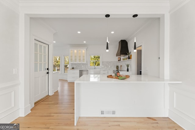 kitchen featuring dishwasher, decorative backsplash, hanging light fixtures, crown molding, and wall chimney range hood