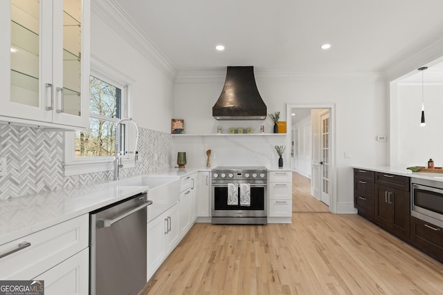 kitchen featuring sink, crown molding, appliances with stainless steel finishes, light hardwood / wood-style floors, and custom range hood