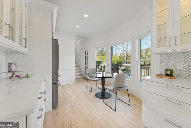 dining area with light hardwood / wood-style flooring and ornamental molding