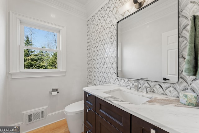 bathroom featuring ornamental molding, toilet, hardwood / wood-style floors, and vanity