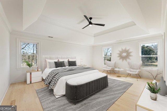 bedroom featuring wood-type flooring, ornamental molding, a raised ceiling, and ceiling fan