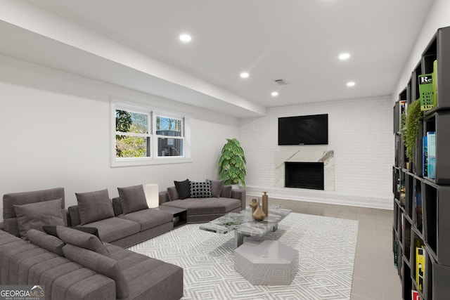 living room with light tile patterned flooring, brick wall, and a brick fireplace