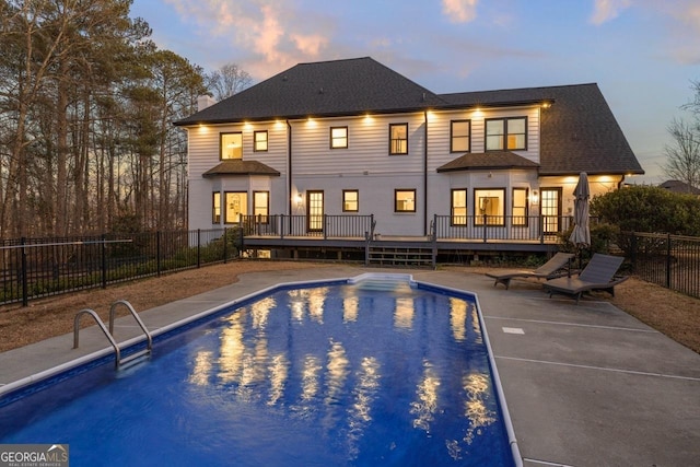 pool at dusk featuring a patio and a deck