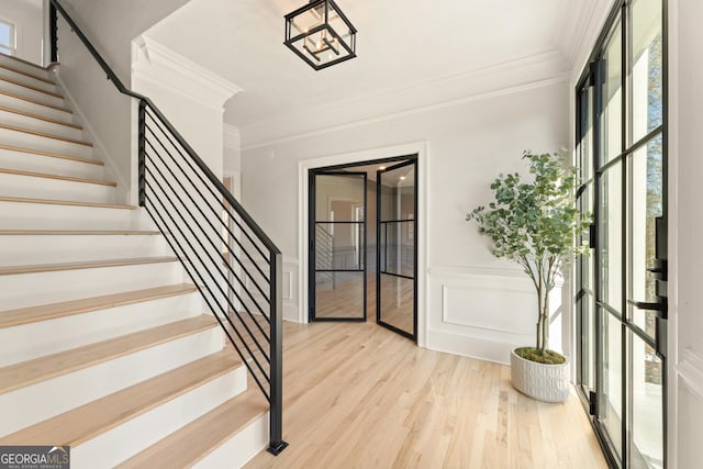 foyer with ornamental molding and light hardwood / wood-style floors