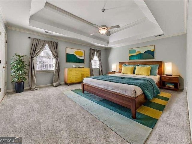 bedroom with multiple windows, a tray ceiling, light carpet, and crown molding