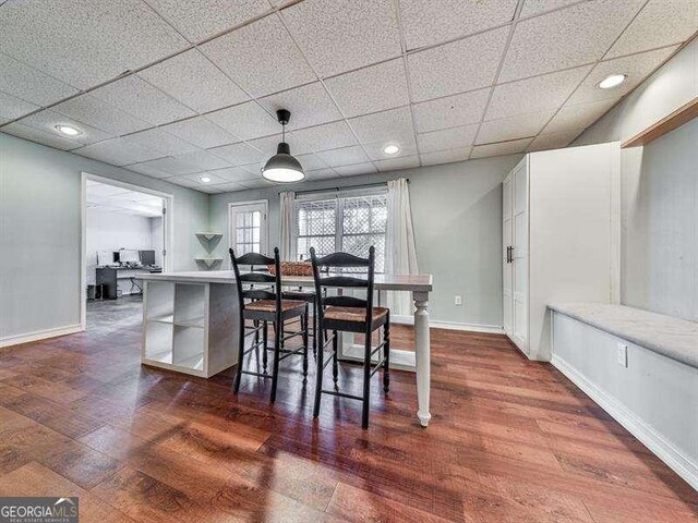 dining room featuring dark hardwood / wood-style flooring and a drop ceiling