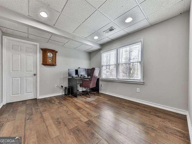 office area with dark hardwood / wood-style floors and a paneled ceiling