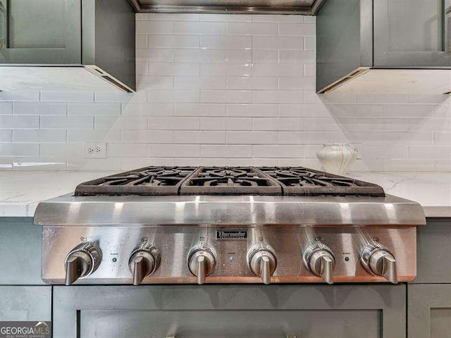 details featuring light stone counters, backsplash, gas stovetop, and extractor fan