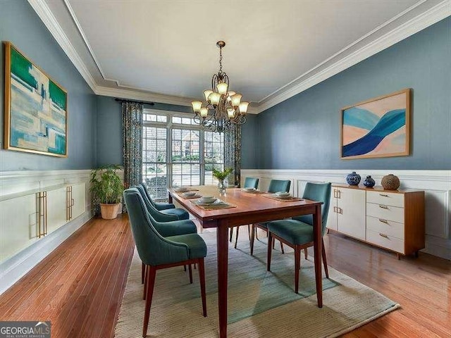 dining area with hardwood / wood-style flooring, crown molding, and a notable chandelier