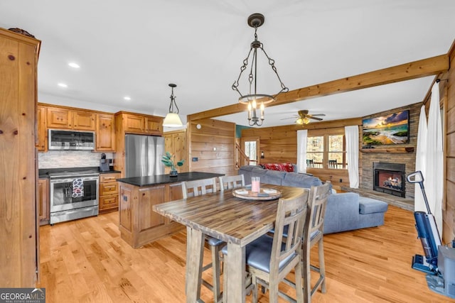 kitchen featuring beam ceiling, decorative light fixtures, stainless steel appliances, and light wood-type flooring