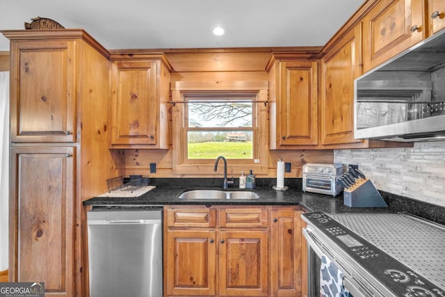 kitchen with stainless steel appliances, sink, decorative backsplash, and dark stone counters