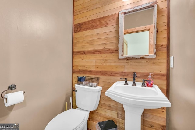 bathroom featuring toilet and wood walls