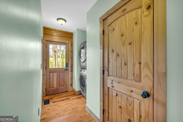 entryway featuring stacked washer / drying machine and light hardwood / wood-style floors