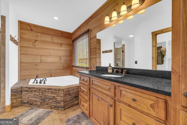 bathroom with tile patterned floors, vanity, wooden walls, and tiled tub